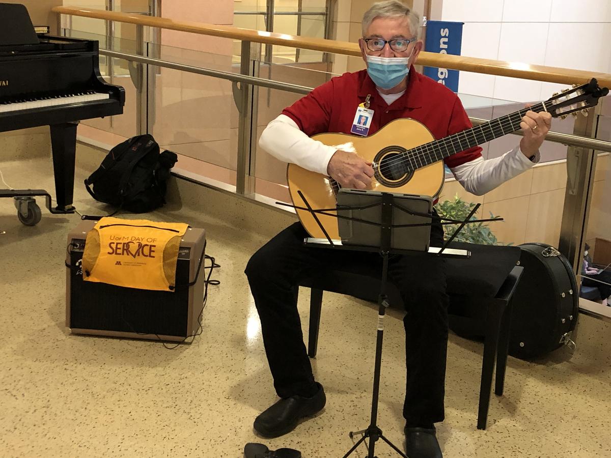 Volunteer playing guitar in Regions Hospital